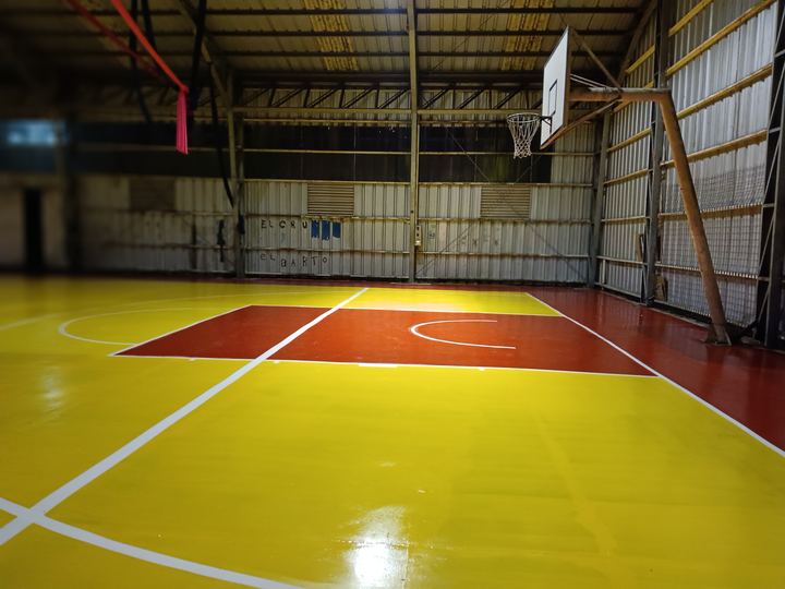 Cancha de básquetbol terminada en amarillo y rojo, con líneas blancas