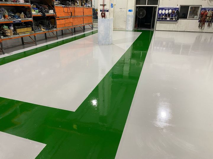 Taller industrial con piso gris, pasillo verde y demarcación amarilla