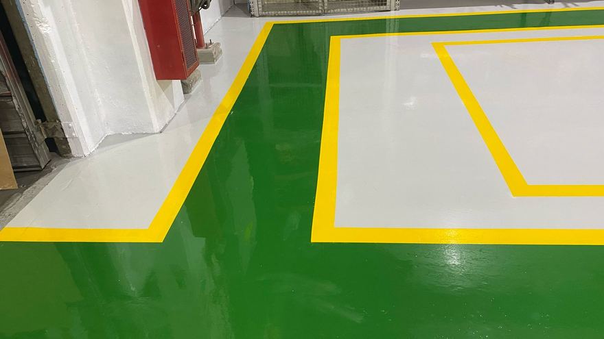 Pasillo verde con líneas amarillas junto a una zona gris demarcada